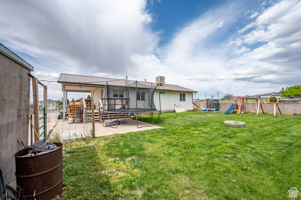 Back of property with a trampoline, a playground, and a patio area