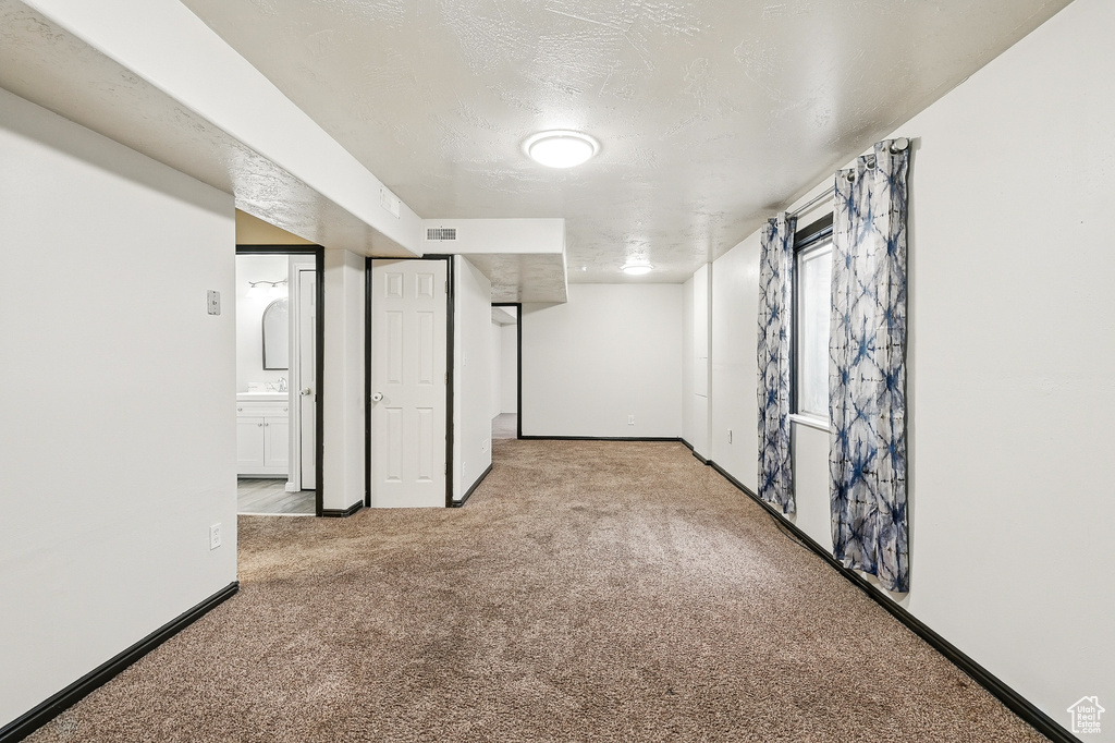 Below grade area with carpet floors, baseboards, and a textured ceiling