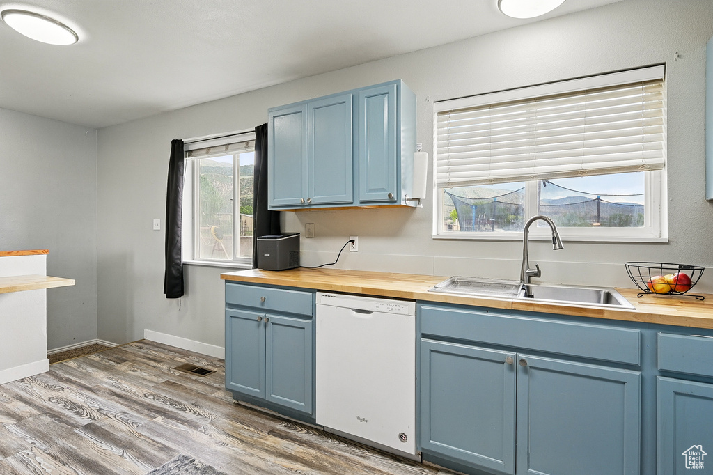 Kitchen with dishwasher, wooden counters, blue cabinetry, and a sink