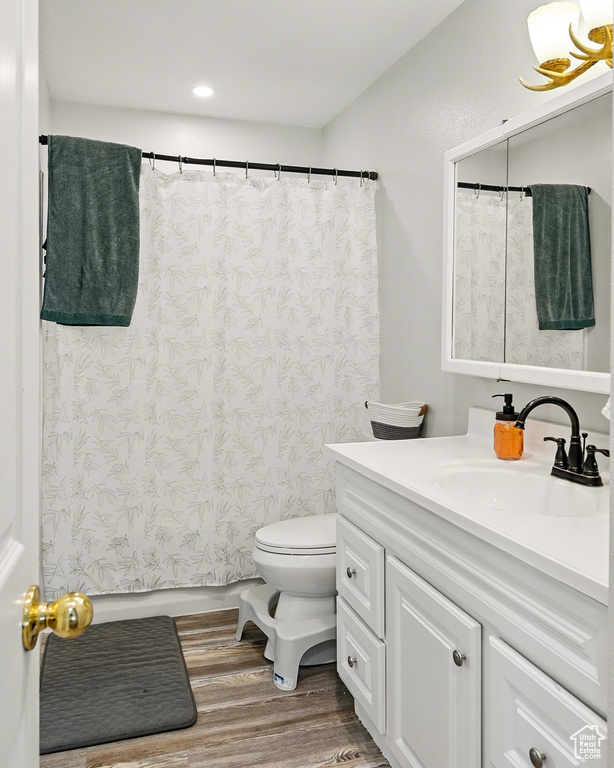Bathroom with vanity, wood finished floors, toilet, recessed lighting, and curtained shower