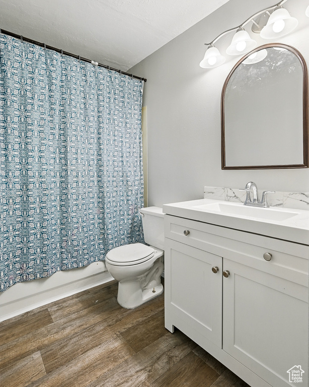 Full bath with toilet, vanity, wood finished floors, and shower / bath combo
