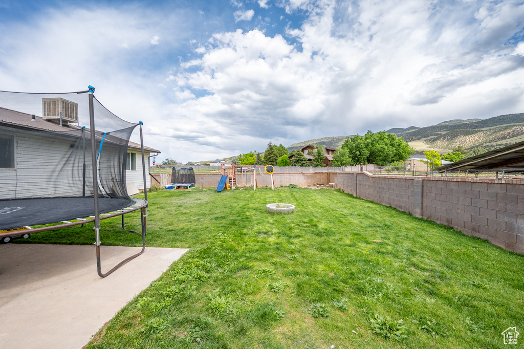 View of yard with a trampoline, a playground, a patio area, and a mountain view