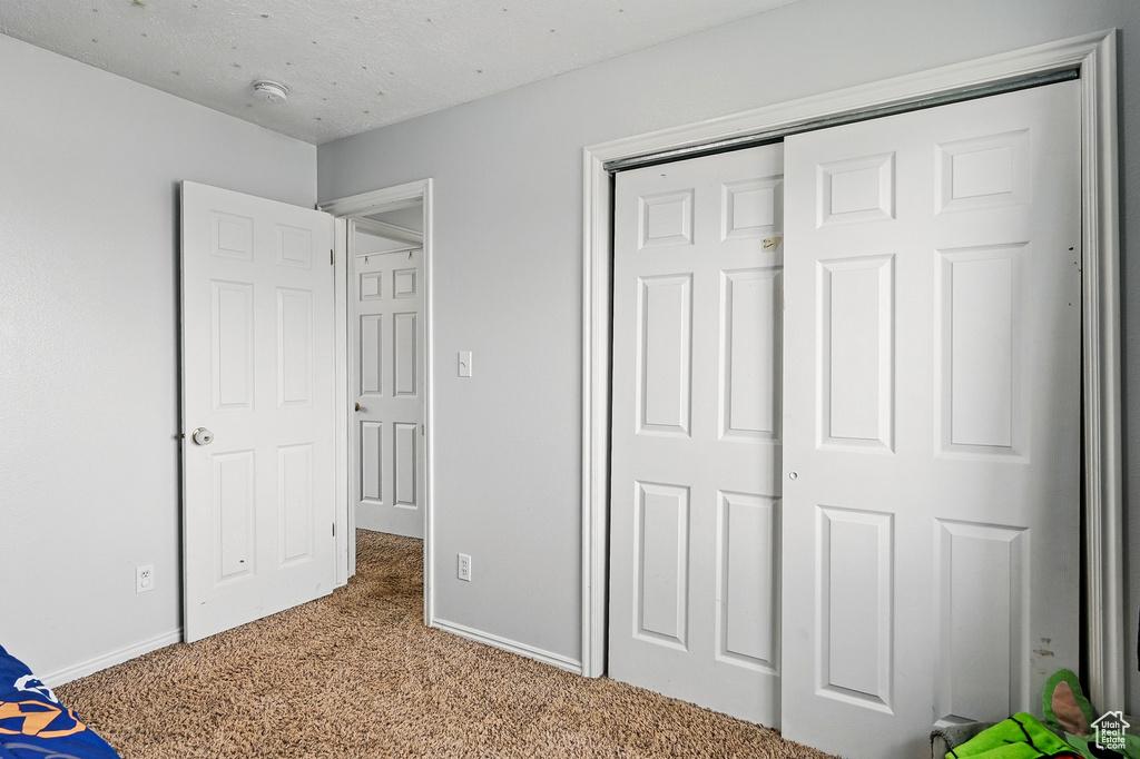 Unfurnished bedroom featuring light colored carpet, baseboards, and a closet