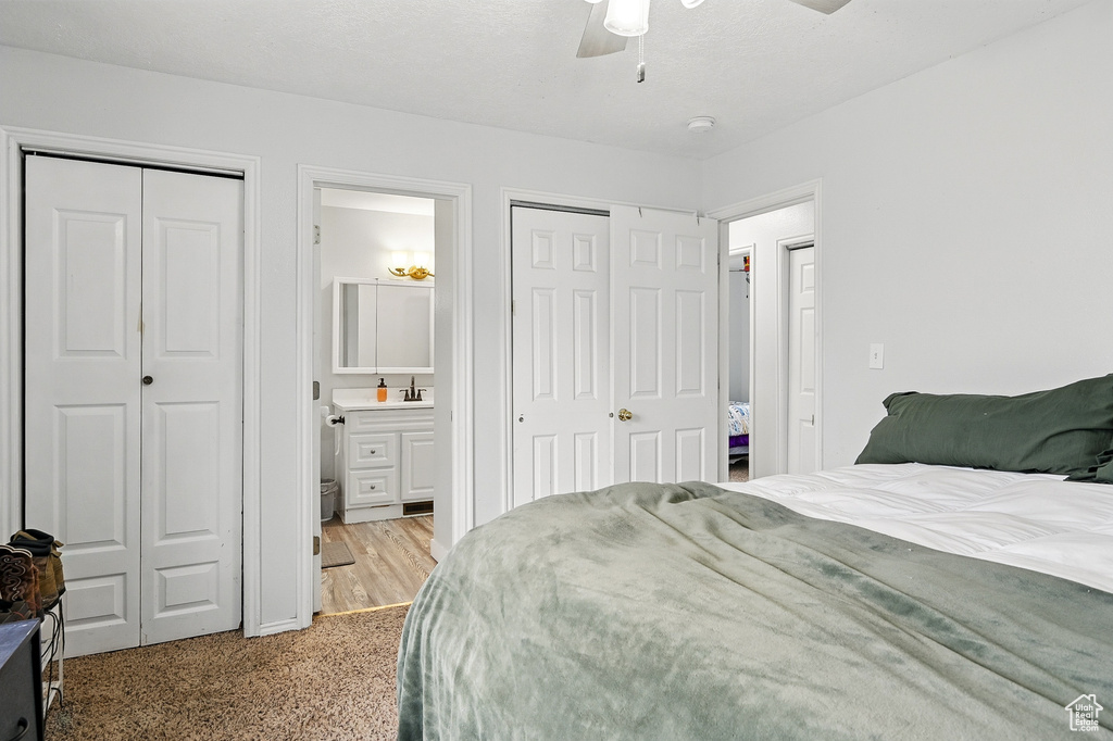 Bedroom featuring multiple closets, ensuite bath, and a ceiling fan