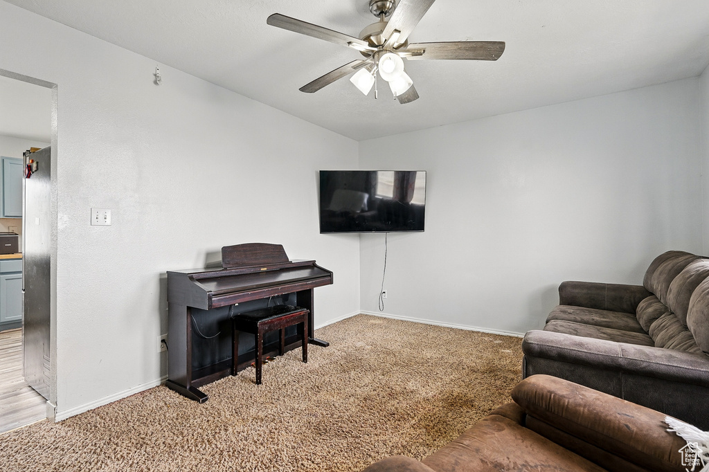 Living area with light colored carpet, baseboards, ceiling fan, and vaulted ceiling