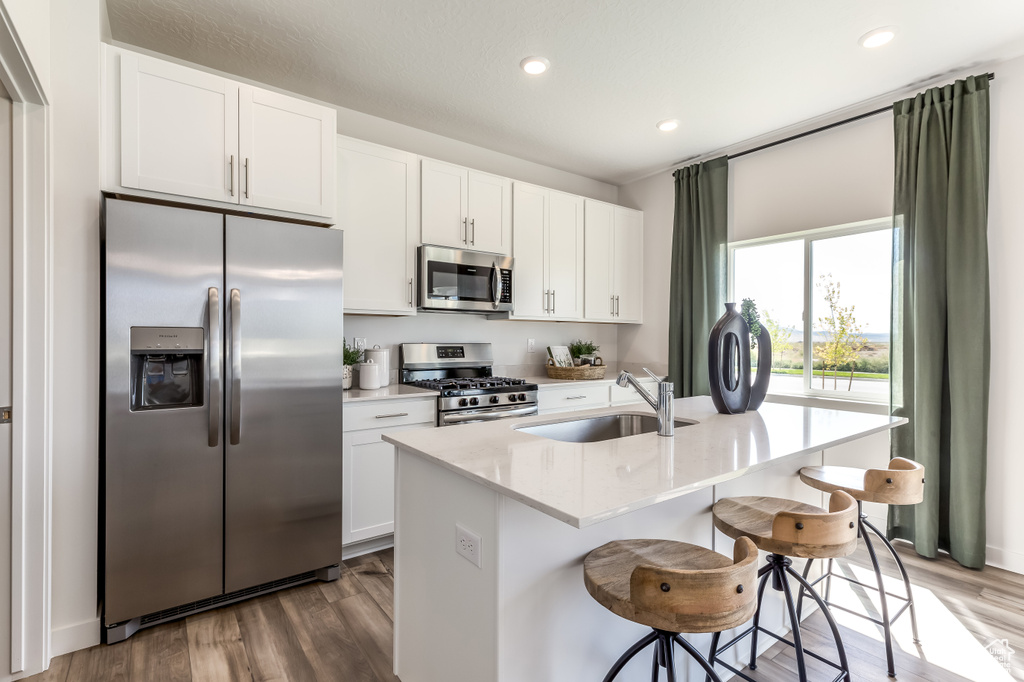 Kitchen featuring stainless steel appliances, a sink, dark wood-type flooring, white cabinets, and recessed lighting