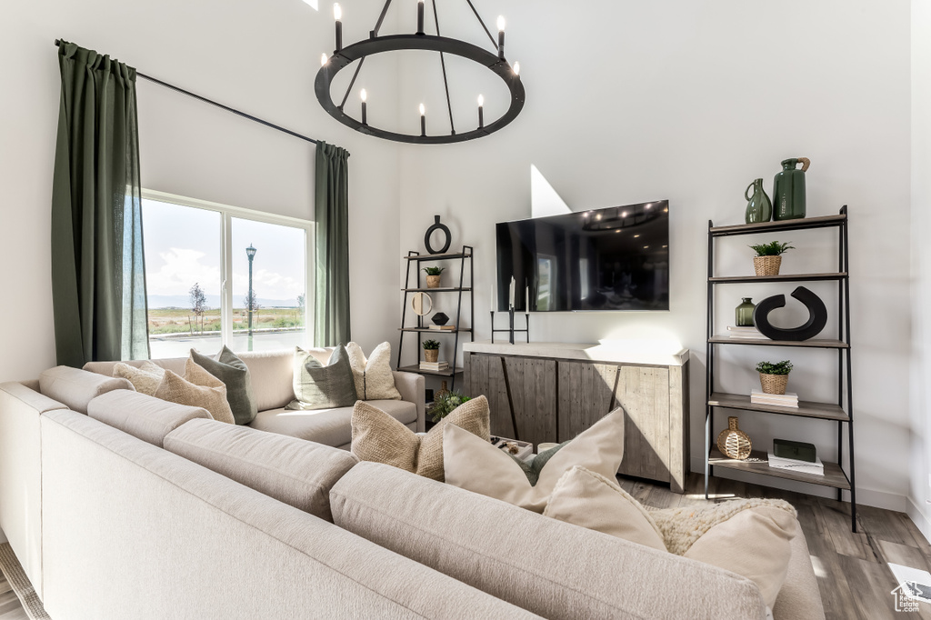 Living area featuring a chandelier, wood finished floors, baseboards, and a high ceiling