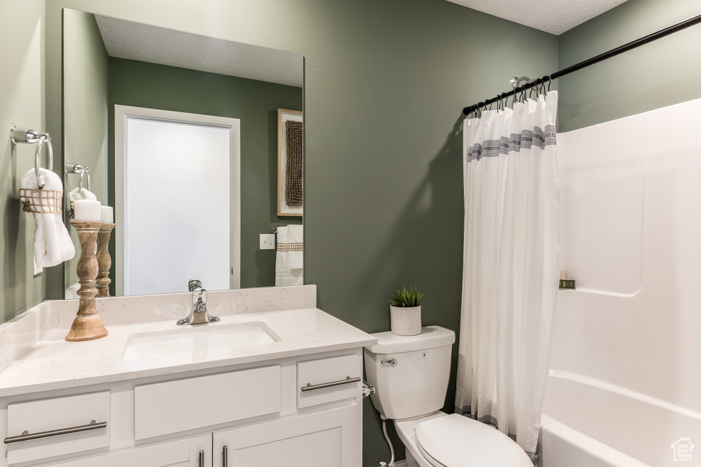 Full bathroom with toilet, vanity, and shower / bath combination with curtain