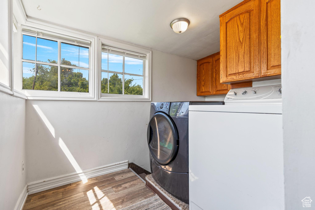 Laundry area featuring cabinet space, washing machine and clothes dryer, wood finished floors, and baseboards