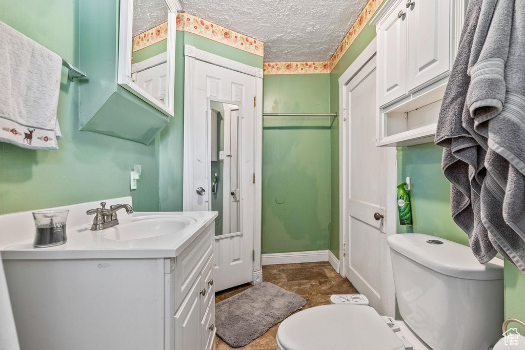Bathroom with vanity, toilet, and a textured ceiling