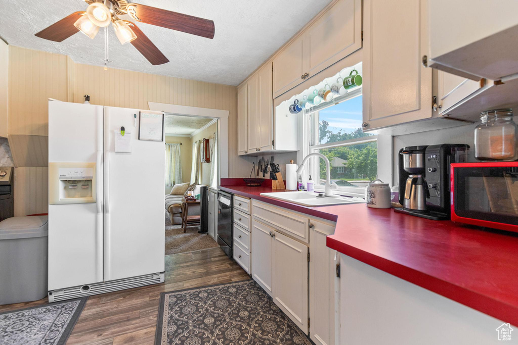 Kitchen featuring white fridge with ice dispenser, a sink, black dishwasher, dark wood-style floors, and ceiling fan