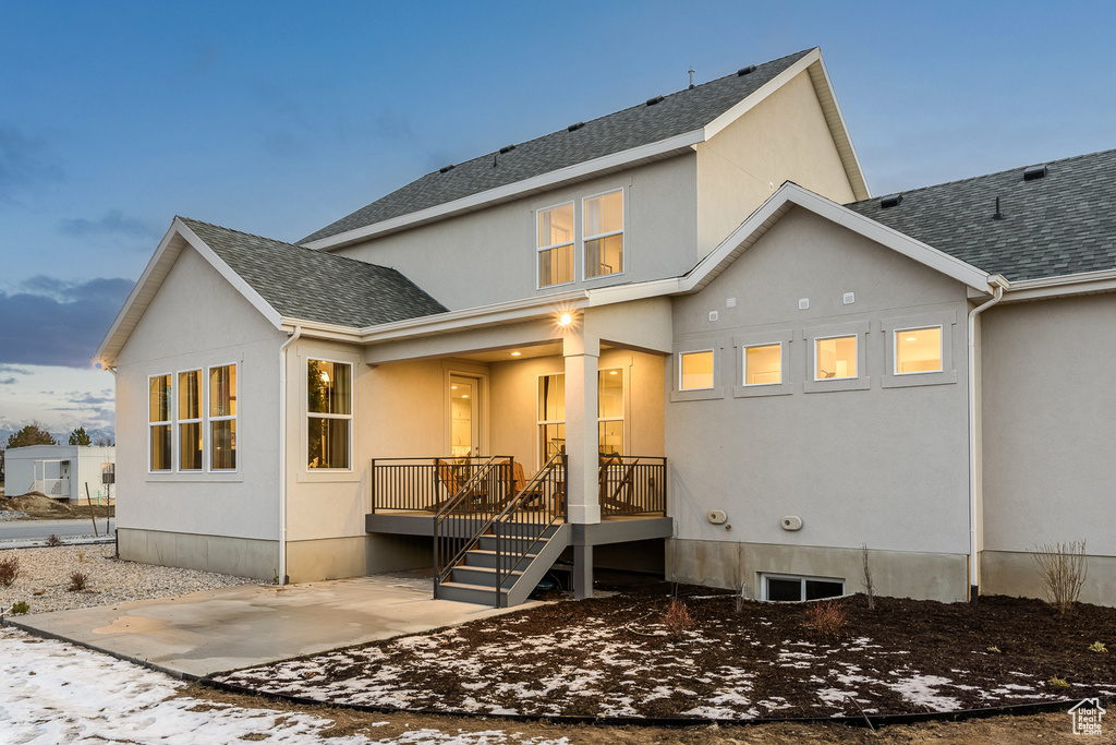 Rear view of property featuring stucco siding and roof with shingles