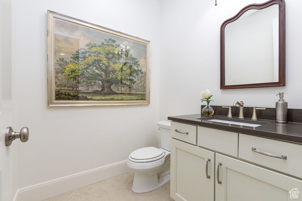 Half bathroom featuring vanity, toilet, and baseboards