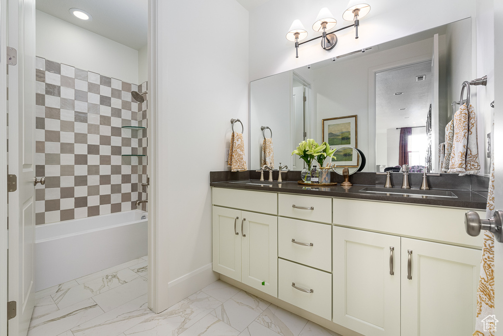 Bathroom with double vanity, bathtub / shower combination, marble finish flooring, and recessed lighting