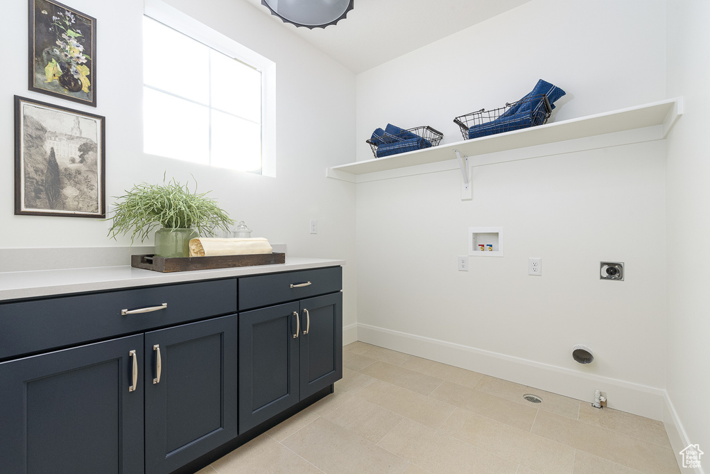 Laundry room featuring electric dryer hookup, washer hookup, cabinet space, baseboards, and light tile patterned flooring