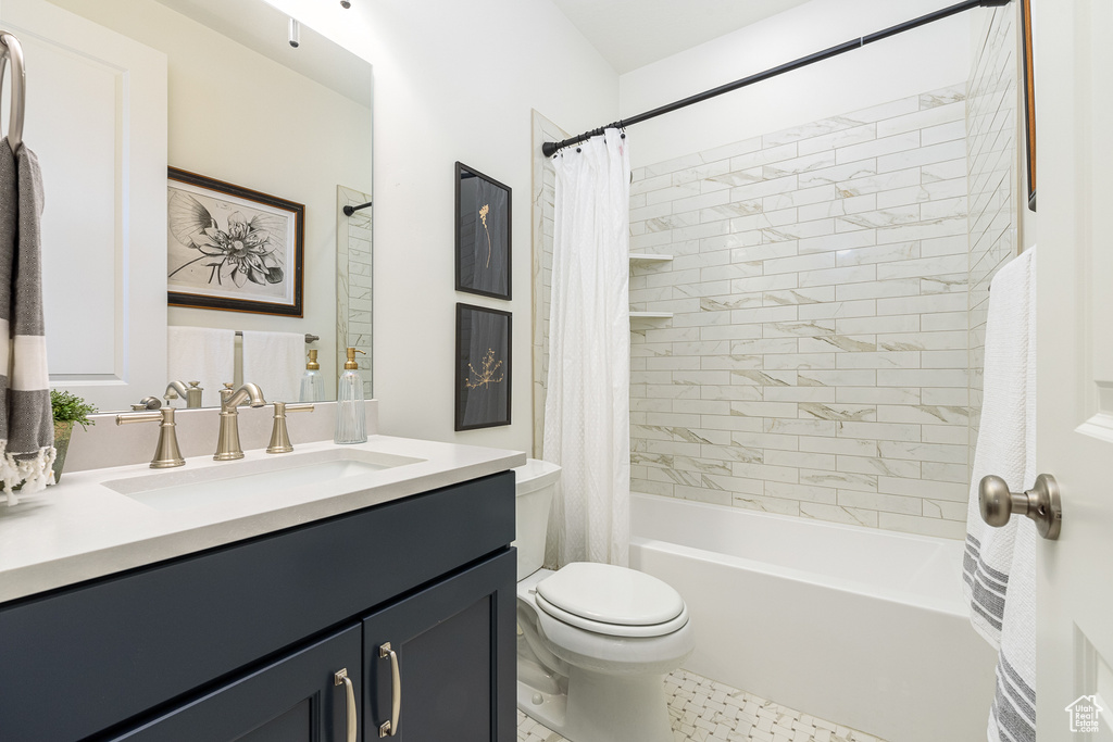 Bathroom featuring vanity, shower / tub combo with curtain, and toilet