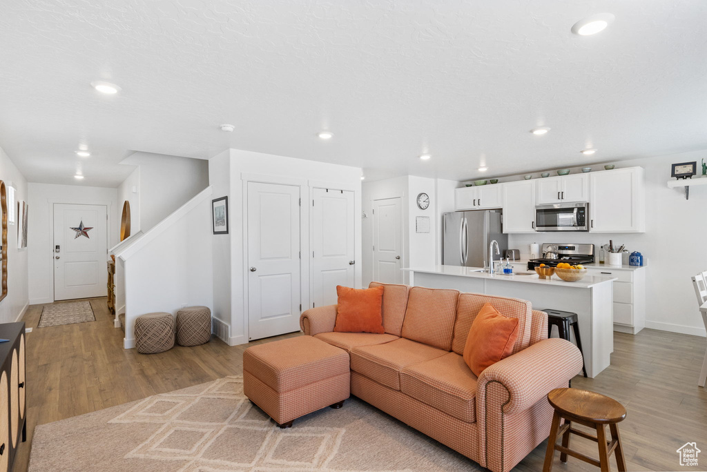 Living area with light wood-style floors, recessed lighting, baseboards, and stairs