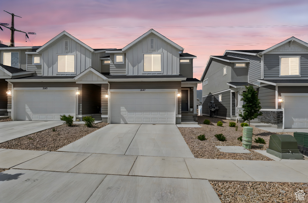 View of front facade with board and batten siding, an attached garage, and driveway