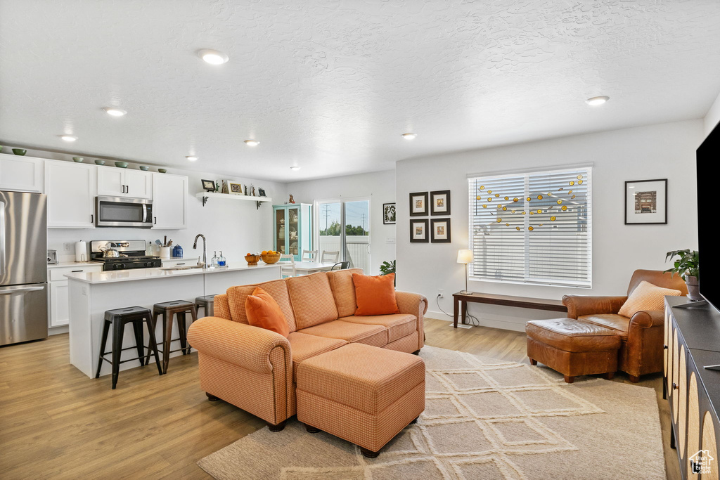 Living area with light wood finished floors, recessed lighting, and a textured ceiling