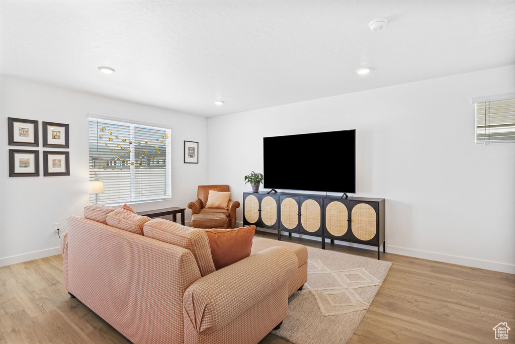 Living room featuring plenty of natural light, light wood-type flooring, baseboards, and recessed lighting