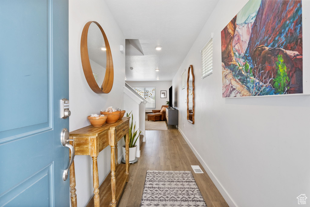 Hallway with wood finished floors, recessed lighting, stairs, and baseboards