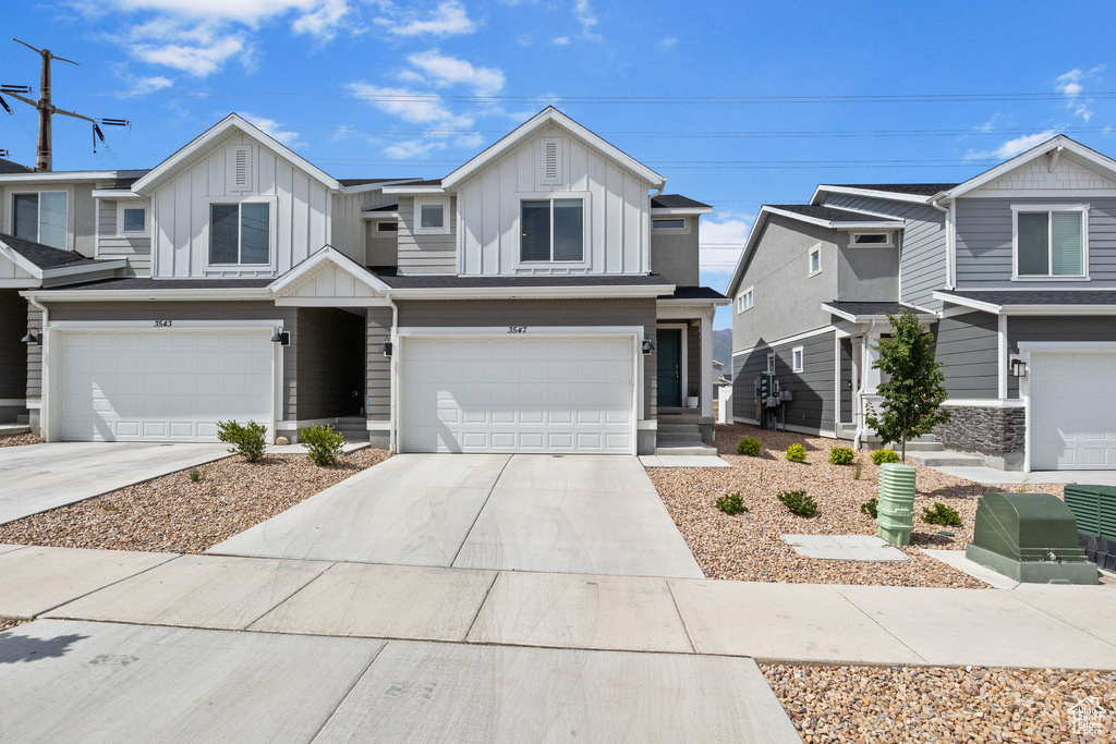 View of front of house with board and batten siding, an attached garage, and driveway