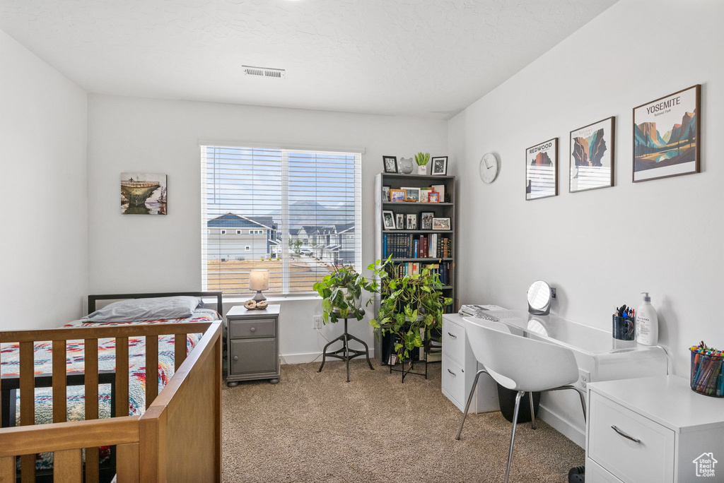 Bedroom featuring light carpet, a desk, and baseboards