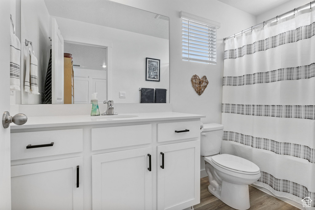 Full bath featuring toilet, vanity, wood finished floors, and a shower with curtain
