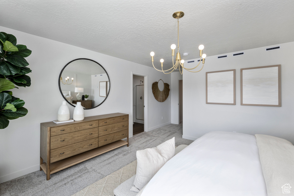 Carpeted bedroom with a chandelier, baseboards, and a textured ceiling