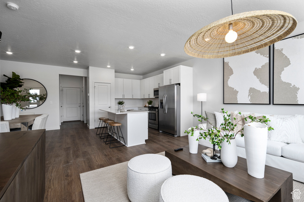 Living room with dark wood finished floors, recessed lighting, and a textured ceiling