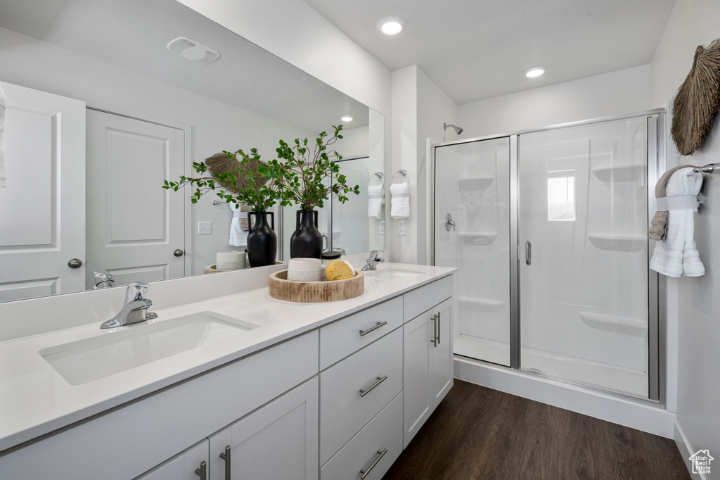 Bathroom with double vanity, a stall shower, wood finished floors, and recessed lighting