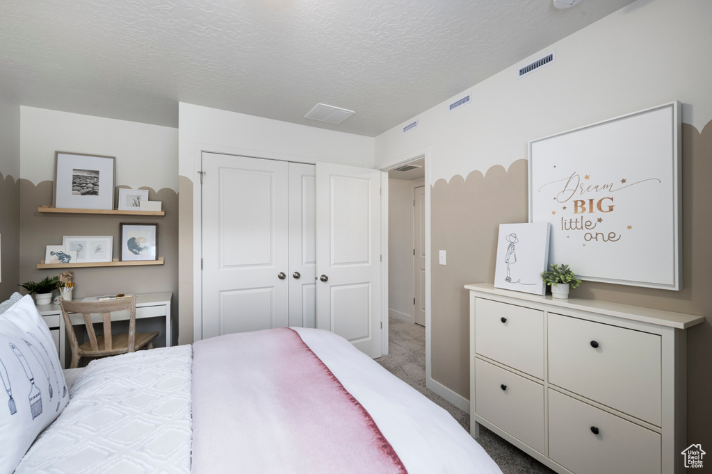 Bedroom with a textured ceiling, carpet, a closet, and baseboards