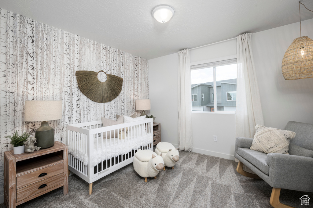Carpeted bedroom featuring a crib and wallpapered walls