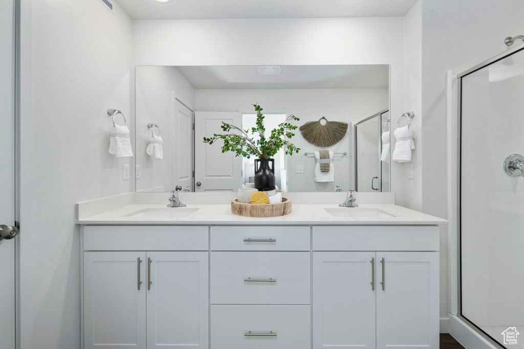 Bathroom featuring a shower stall and double vanity