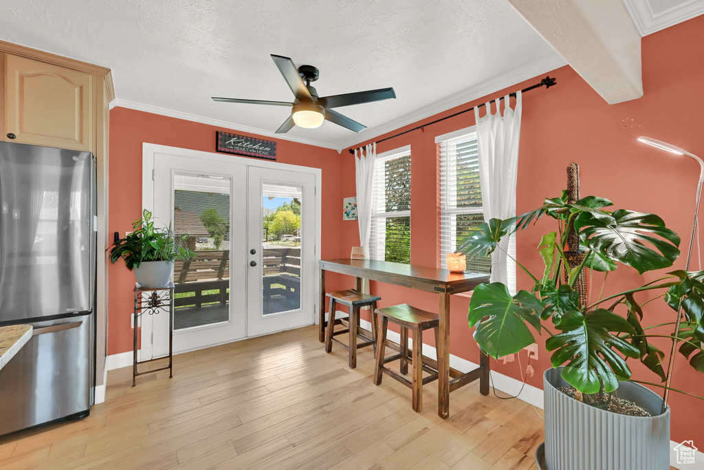 Dining space featuring french doors, a ceiling fan, crown molding, light wood-style floors, and a textured ceiling