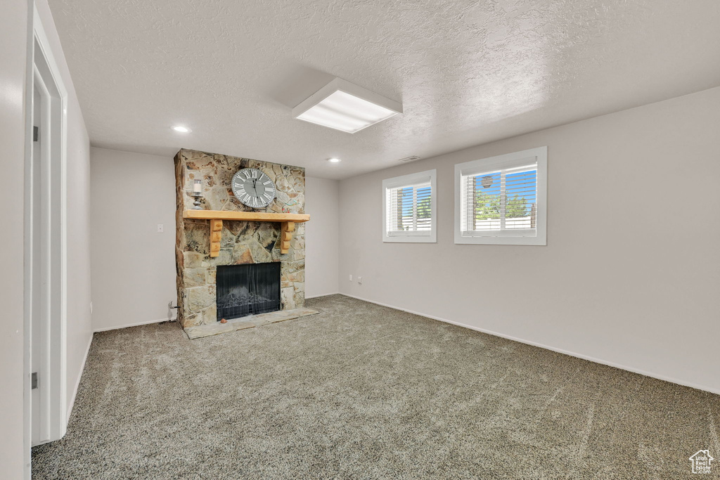 Unfurnished living room with a fireplace, carpet floors, a textured ceiling, recessed lighting, and baseboards