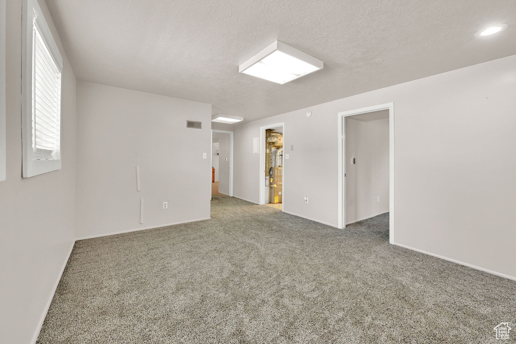 Unfurnished room with carpet, baseboards, and a textured ceiling