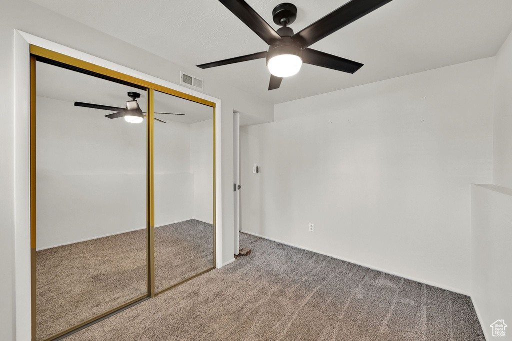 Unfurnished bedroom featuring carpet flooring, a closet, and ceiling fan