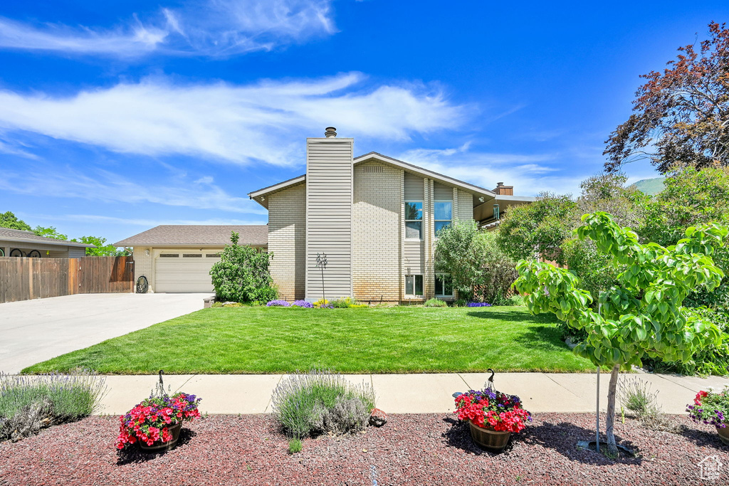 View of front of home featuring concrete driveway, an attached garage, and a chimney