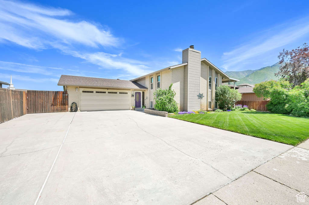 View of front of home with a garage, driveway, a mountain view, a chimney, and brick siding
