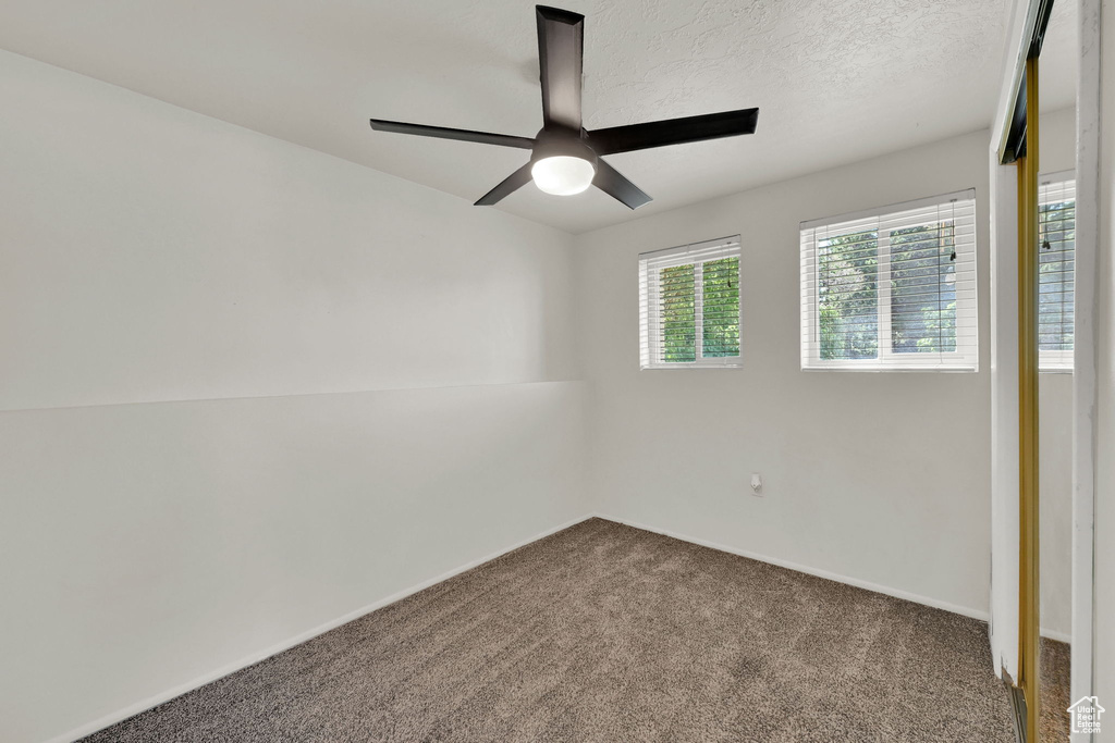 Carpeted empty room featuring ceiling fan, baseboards, and a textured ceiling