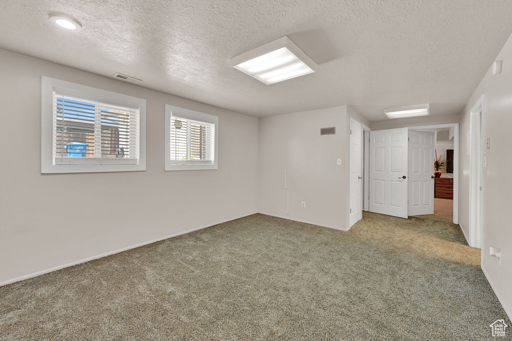 Carpeted empty room featuring a textured ceiling