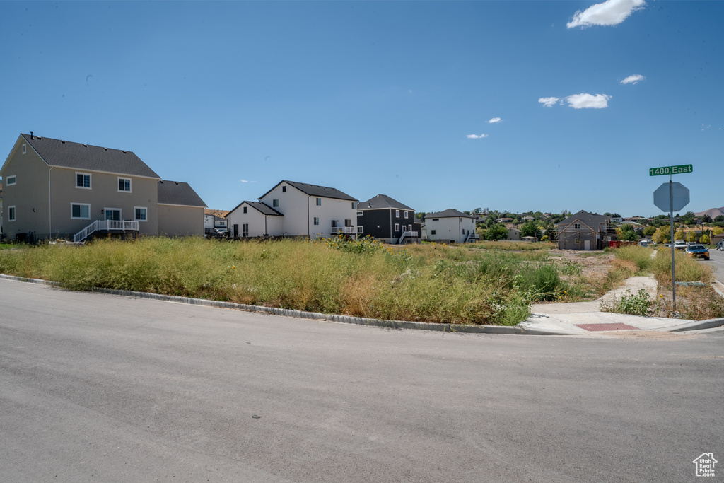View of asphalt street featuring curbs, a residential view, and traffic signs