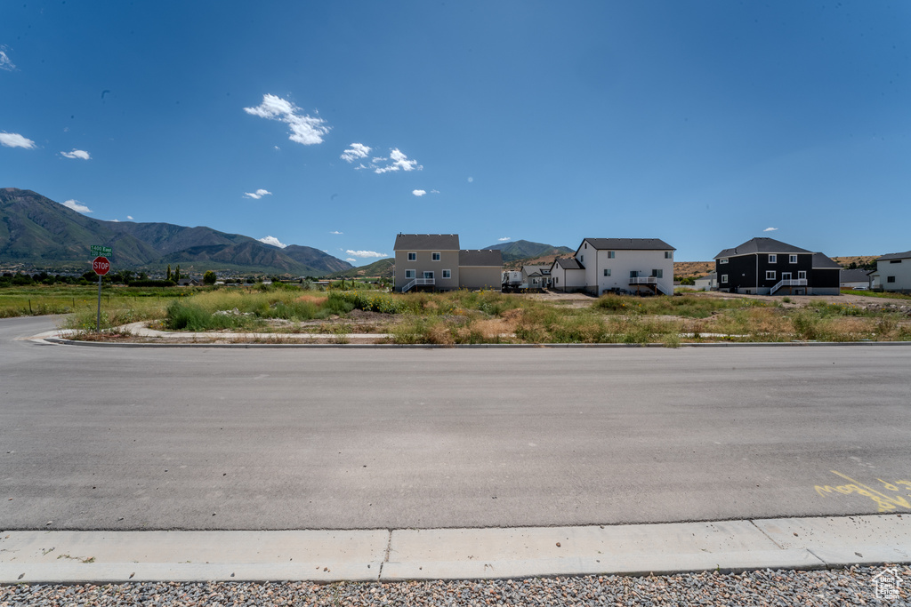 View of asphalt street with curbs, a mountain view, traffic signs, and a residential view