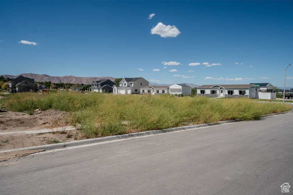 View of asphalt street featuring a residential view, curbs, street lights, and a mountain view