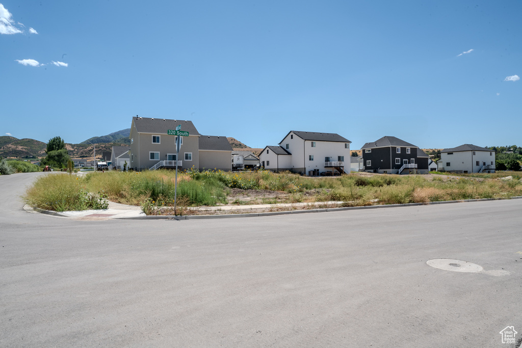 View of asphalt street with curbs, a residential view, and a mountain view