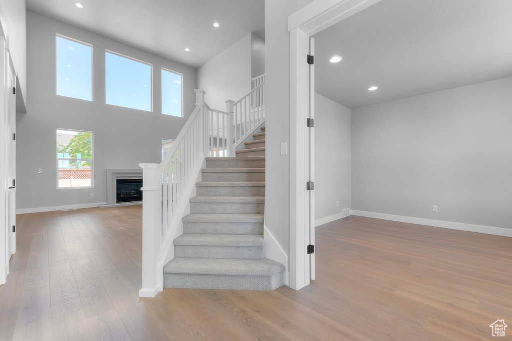 Staircase with wood finished floors, a fireplace with raised hearth, baseboards, and recessed lighting
