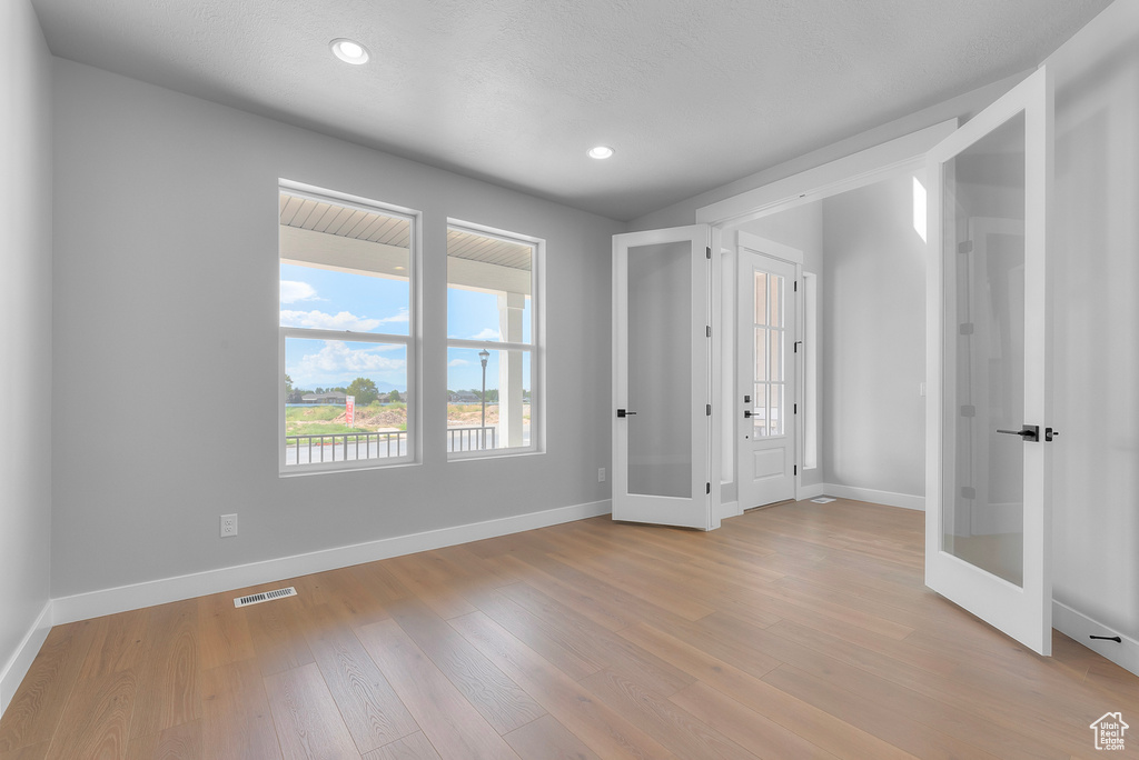 Unfurnished bedroom with baseboards, light wood-type flooring, recessed lighting, and french doors