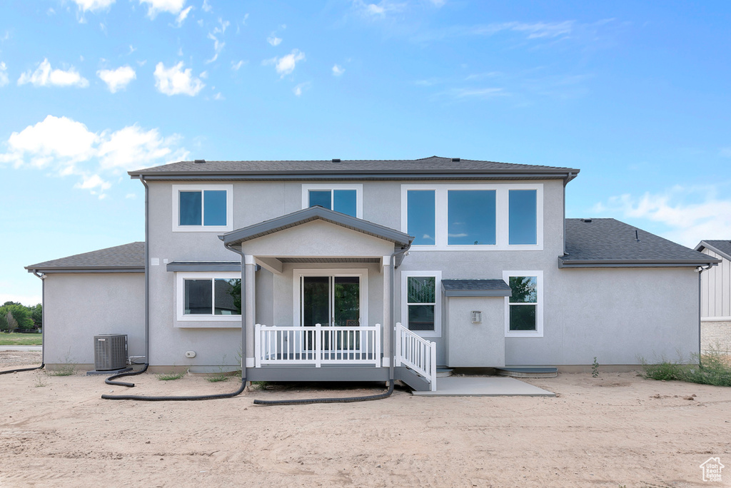 Rear view of house featuring cooling unit and stucco siding
