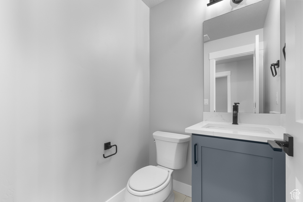 Half bathroom featuring toilet, vanity, and baseboards